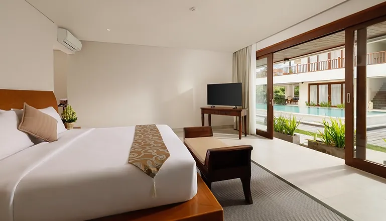 Serene bedroom features a large bed and sliding doors to outdoor pool at The Bija Villas