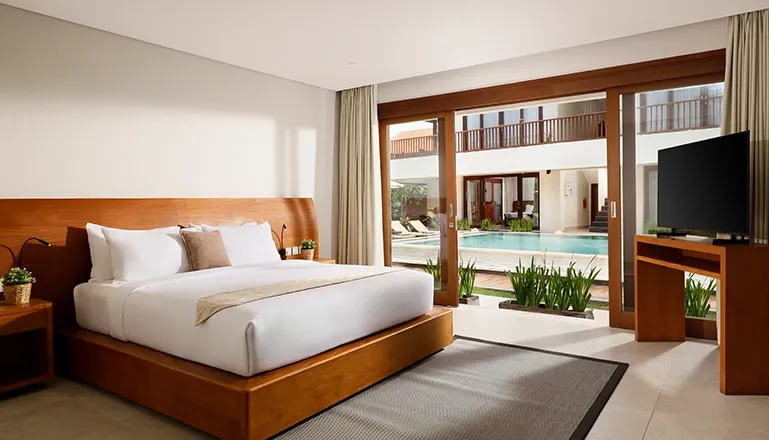 Spacious bedroom features a comfortable bed and sliding doors to pool at The Bija Villas