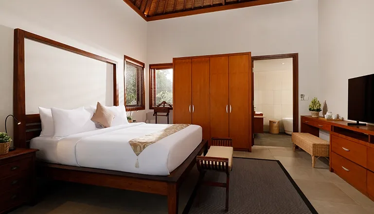 Spacious bedroom features a wooden bed and direct entrance to bathroom at The Bija Villas