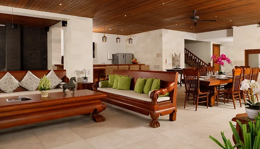 Traditional Balinese open-plan living area with wooden furniture, a dining space, and ornate decor at The Bija Villas