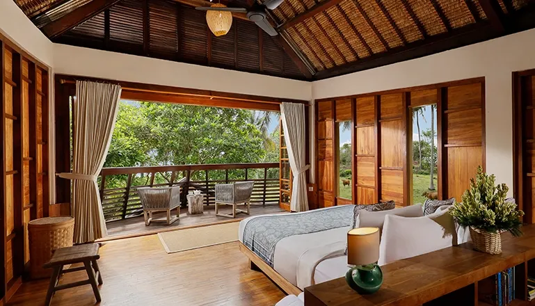 Bedroom features comfortable bed and expansive doors to private tropical outdoors at The Cove Bali