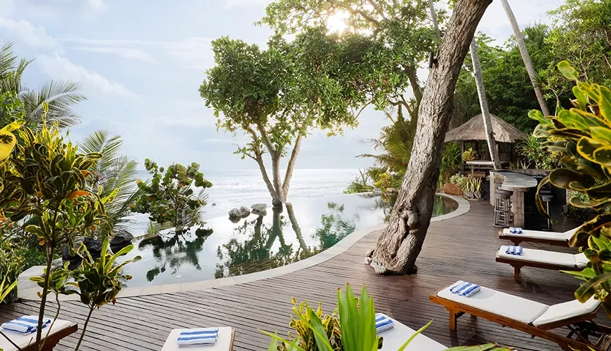 Luxurious infinity pool features stunning ocean views and natural trees at The Cove Bali