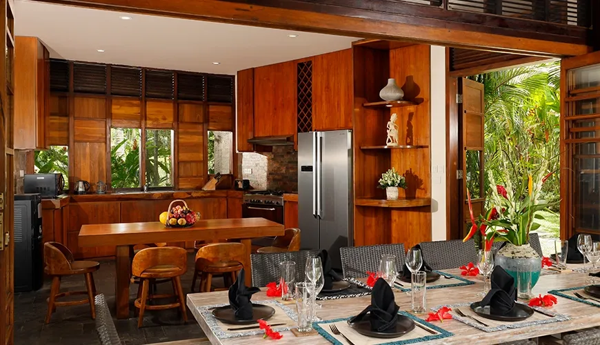 Modern kitchen features wooden cabinetry and integrated outdoor dining space at The Cove Bali