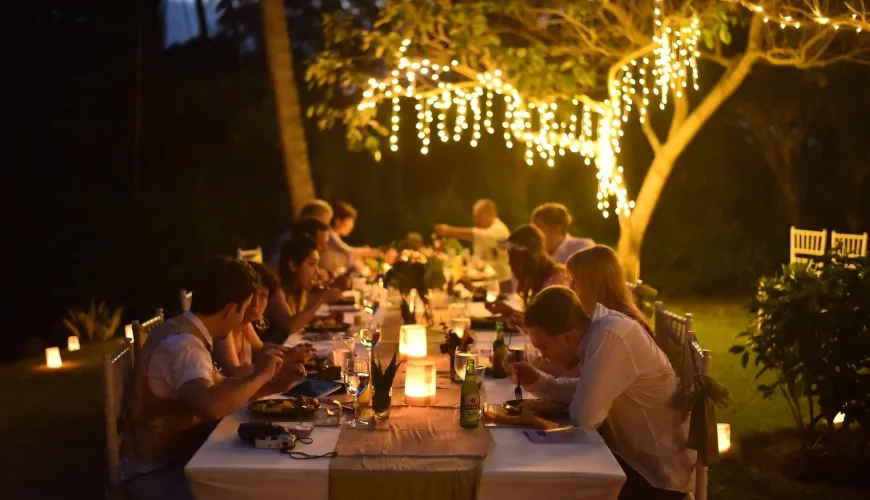Night shot of friends enjoying communal dinner under twinkling lights at The Cove Bali