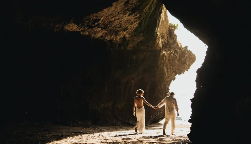 Silhouette of newlywed couple holding hands in a sunlit beach cave at The Cove Bali