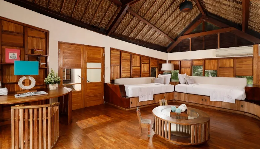 Warm wooden media room with cozy daybeds and rustic furniture at The Cove Bali Villa