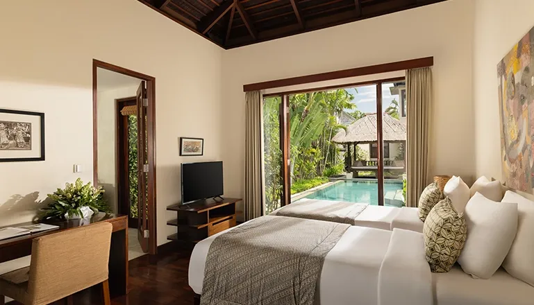 Bedroom with twin beds desk and stunning pool garden view at The Suar Seminyak
