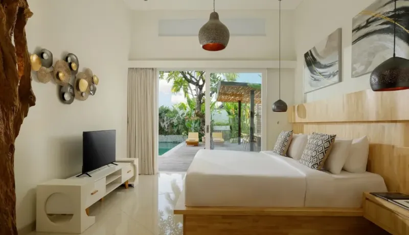 Bright master bedroom with a large bed, modern art, and sliding doors to the pool at The Suar Sanur