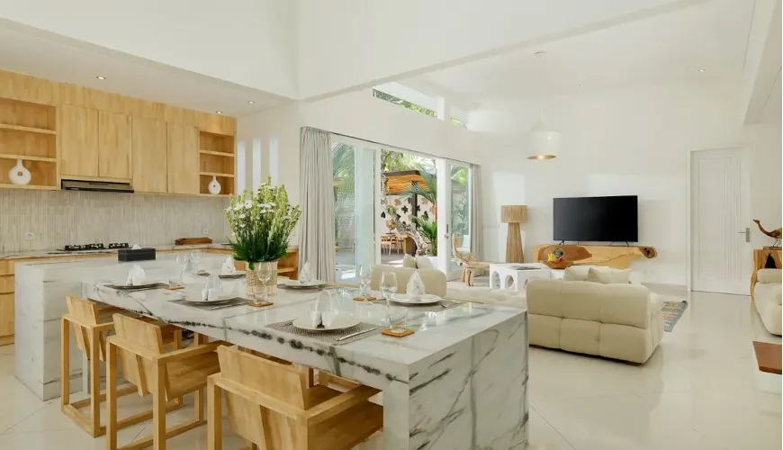 Elegant dining area featuring a long marble table, wooden chairs, and views of living area at The Suar Sanur
