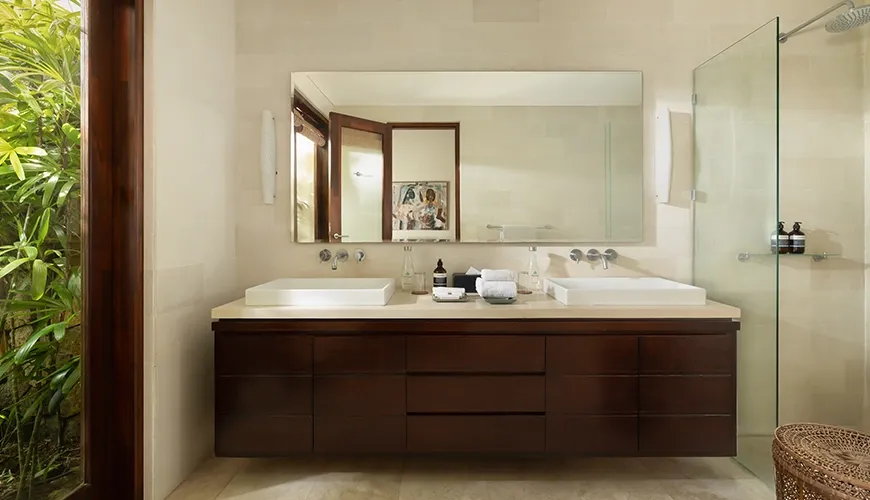 Luxurious bathroom area with a sleek dark wood vanity and a view of lush tropical greenery at The Suar Seminyak