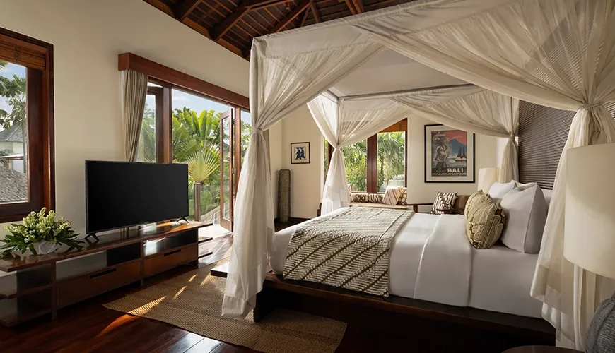 Luxurious master bedroom with four poster bed and tropical garden views at The Suar Seminyak