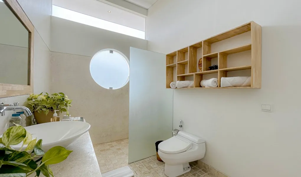 Bright, modern bathroom with a walk-in shower and wooden vanity at The Suar Sanur