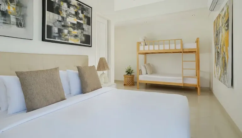 Spacious bedroom featuring a large bed, bunk bed, and modern artwork, ideal for families at The Suar Sanur
