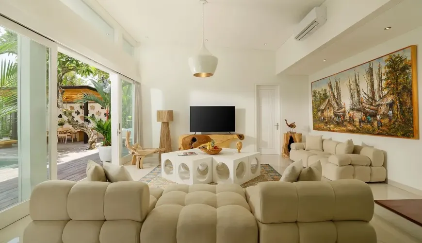 Spacious lounge with a large white Camelonda sofa, modern art, and glass doors at The Suar Sanur