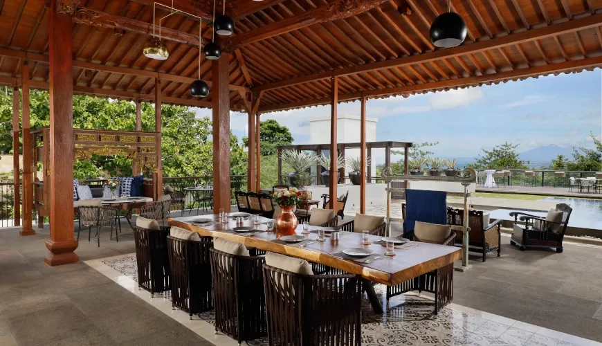 Spacious outdoor dining area with a long table and seating at The Tulou Bali Villa