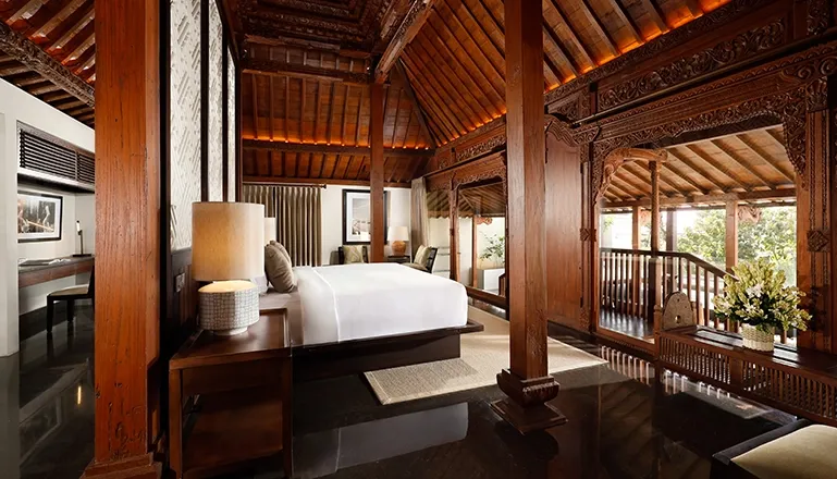 Elegant Bali bedroom with intricate wood carvings at The Tulou