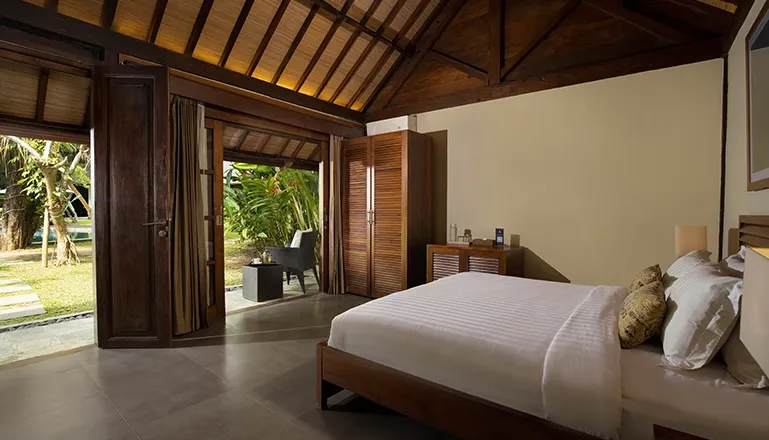 Spacious bedroom featuring warm lighting and a comfortable bed at Tirtadari Villa
