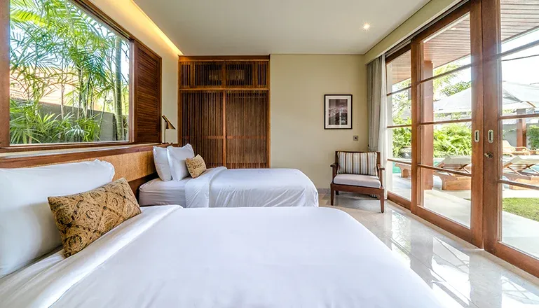 Cozy room featuring twin bed with wooden frame at Uma Berawa Villa