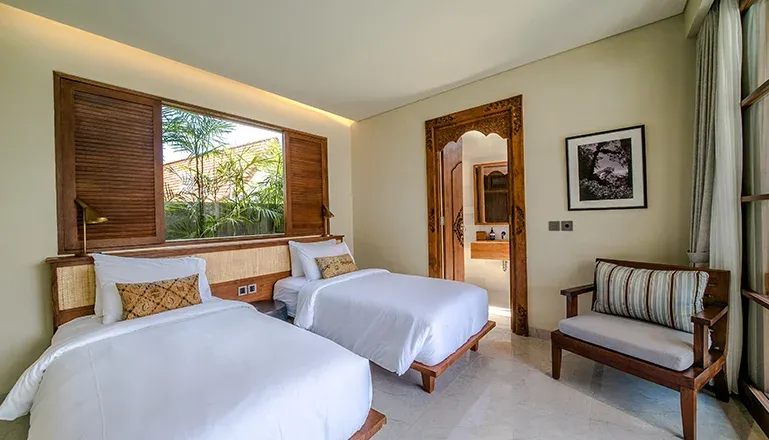 Twin bedroom with wooden accents and pool view at Uma Berawa Villa