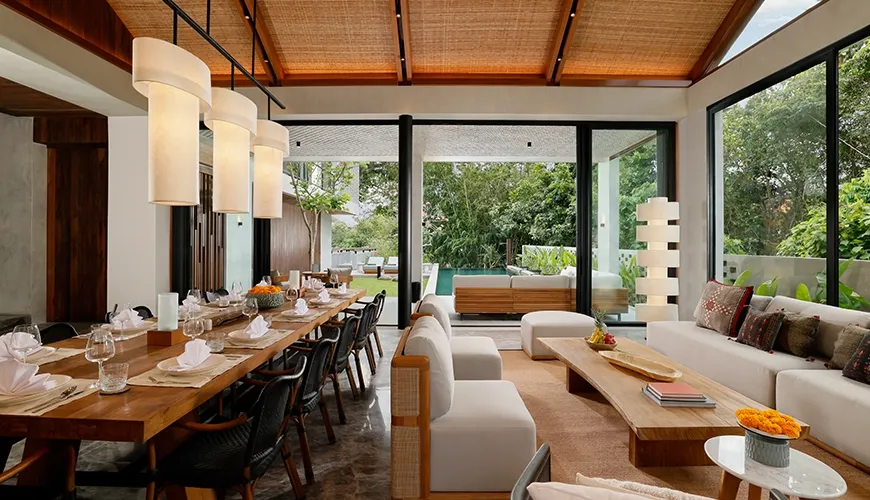 Beautifully decorated living room and dining area with glass doors leading to a private swimming pool at Uma Santai Canggu