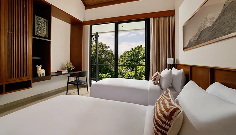 Comfortable twin bedroom inside a luxury villa with two beds, a small desk, and a bright view of the outdoors at Uma Santai Canggu