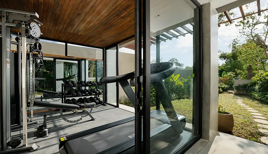 Fully equipped private gym inside a luxury villa with a treadmill and a beautiful outdoor view at Uma Santai Canggu
