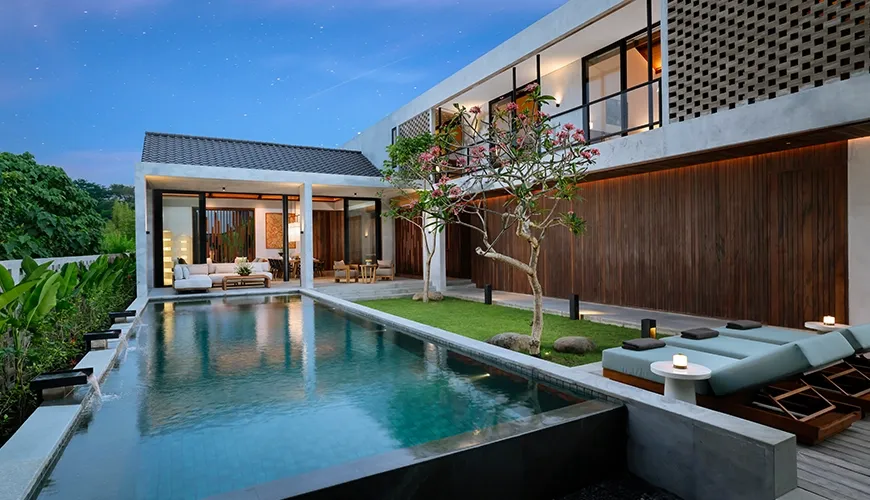 Luxurious modern villa at dusk with a beautiful long swimming pool and comfortable lounge chairs at Uma Santai Canggu