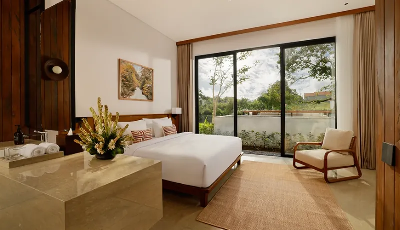 Spacious master bedroom inside a modern villa with an inviting bed and a large window facing greenery at Uma Santai Canggu