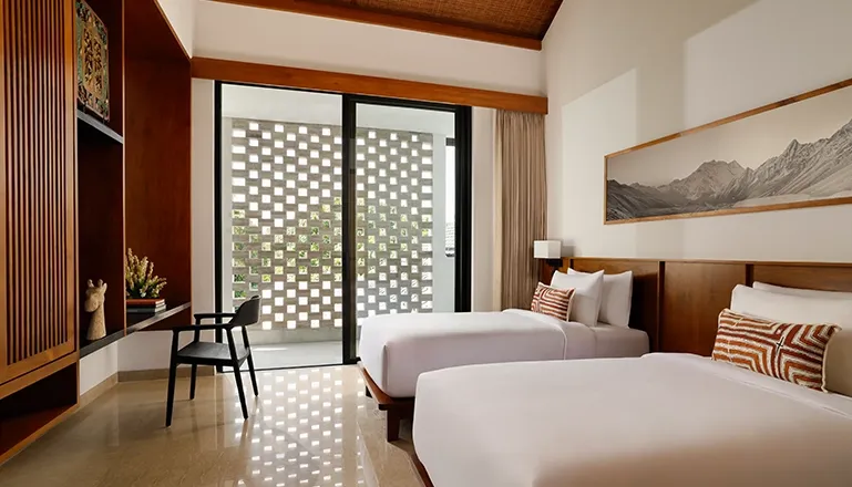 Spacious twin bedroom with two comfortable beds and a sliding glass door leading to a private outdoor space at Uma Santai Canggu