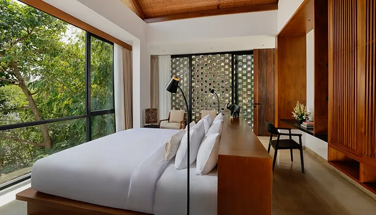 Stylish and spacious villa bedroom with a large bed and big windows showing green trees at Uma Santai Canggu