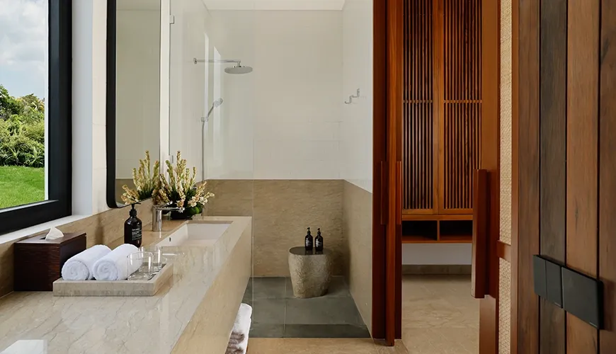 Contemporary bathroom with wooden cabinet details and a sleek stone countertop next to an open-concept shower at Uma Santai Canggu