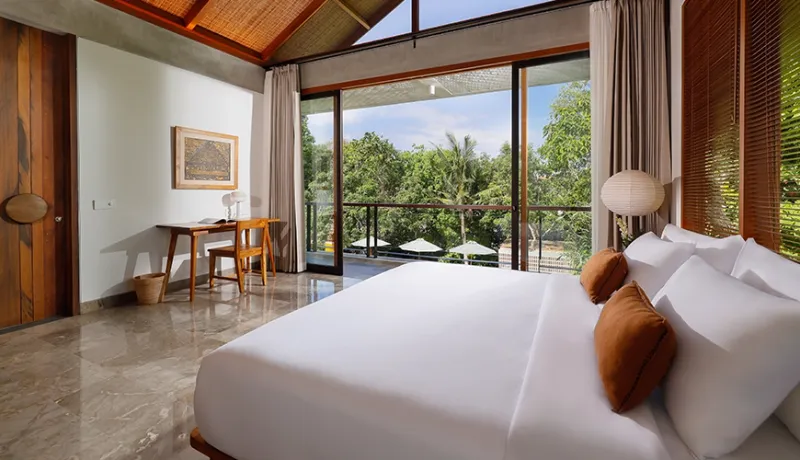 Contemporary villa bedroom featuring a vaulted thatched roof king bed and scenic jungle treetop view balcony at Uma Santai Pererenan