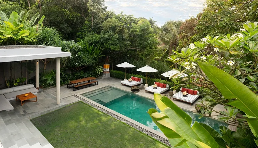 Stunning elevated view of a luxury villa pool surrounded by lush tropical trees and landscaping at Uma Santai Pererenan