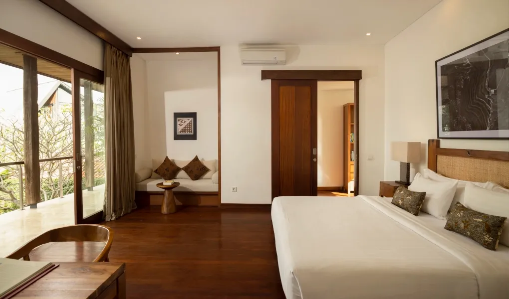 Comfortable bedroom featuring dark wood floors and balcony access at Villa Ambara