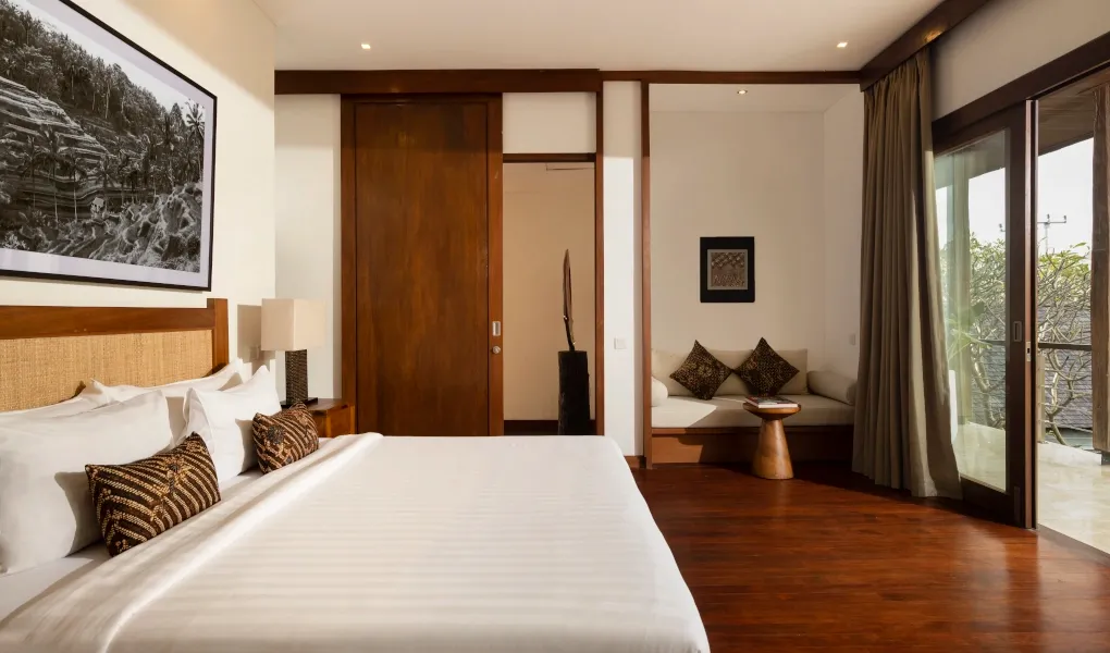 Cozy bedroom with dark wood floors and a private balcony at Villa Ambara