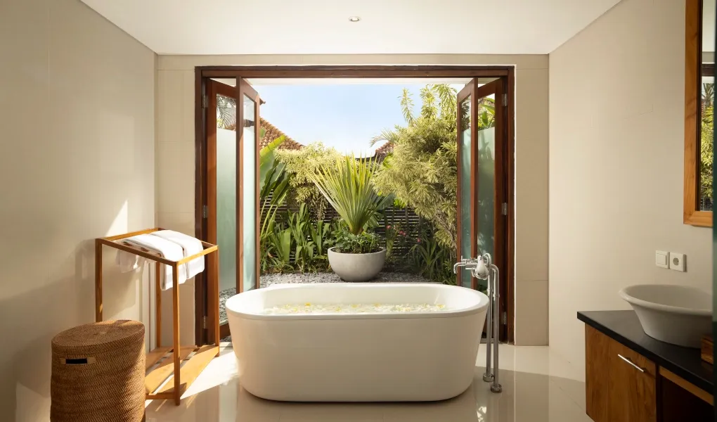 Luxurious bathroom with an outdoor soaking tub and lush garden view at Villa Ambara