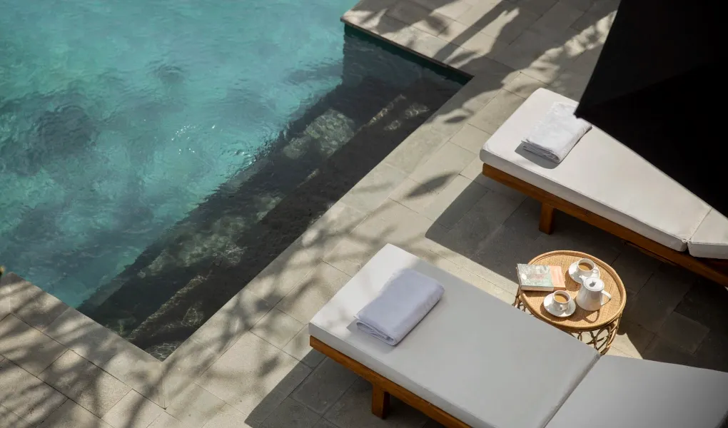 Sunbeds with towels by a tranquil swimming pool at Villa Ambara