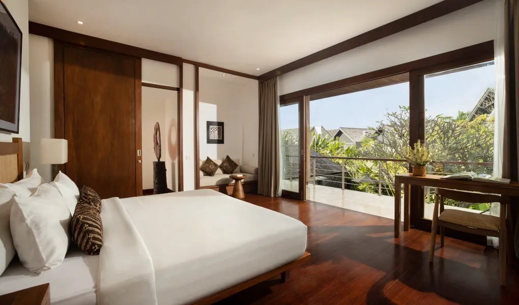 Tropical bedroom with rich wood flooring and a beautiful balcony view at Villa Ambara