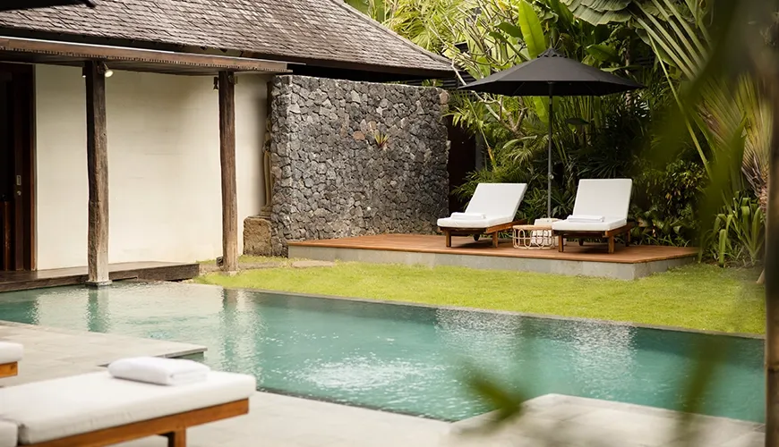 Tropical pool area with sun loungers and traditional villa at Villa Ambara
