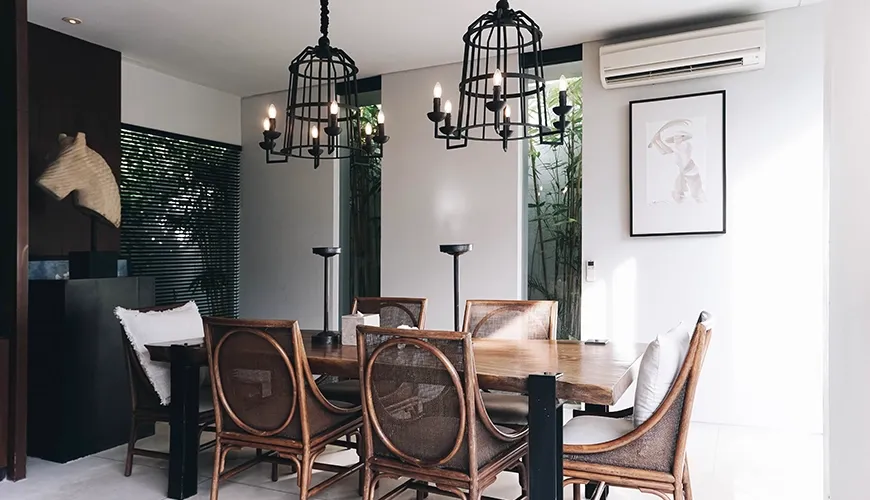 Elegant dining area features a wooden table and stylish cage chandeliers at Villa Ambergris