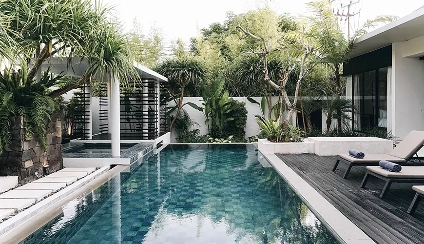 Modern pool features serene water, sun loungers, and lush tropical plants at Villa Ambergris