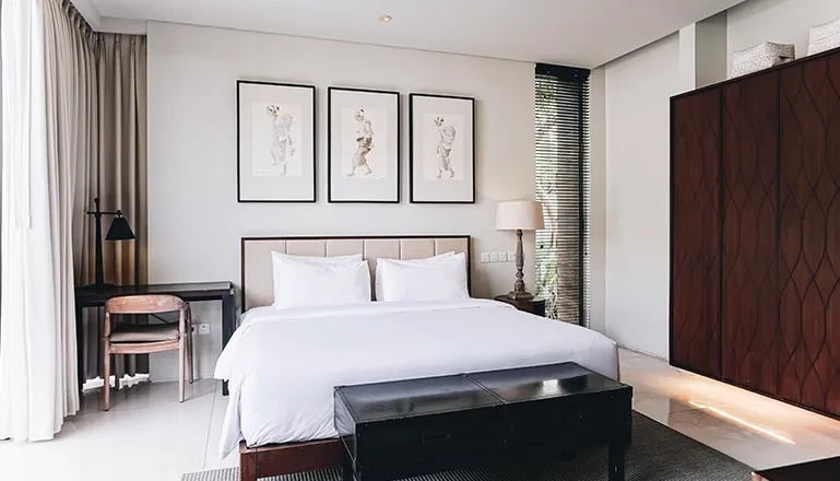 Spacious bedroom features a comfortable bed, art, and patterned wooden wardrobe at Villa Ambergris