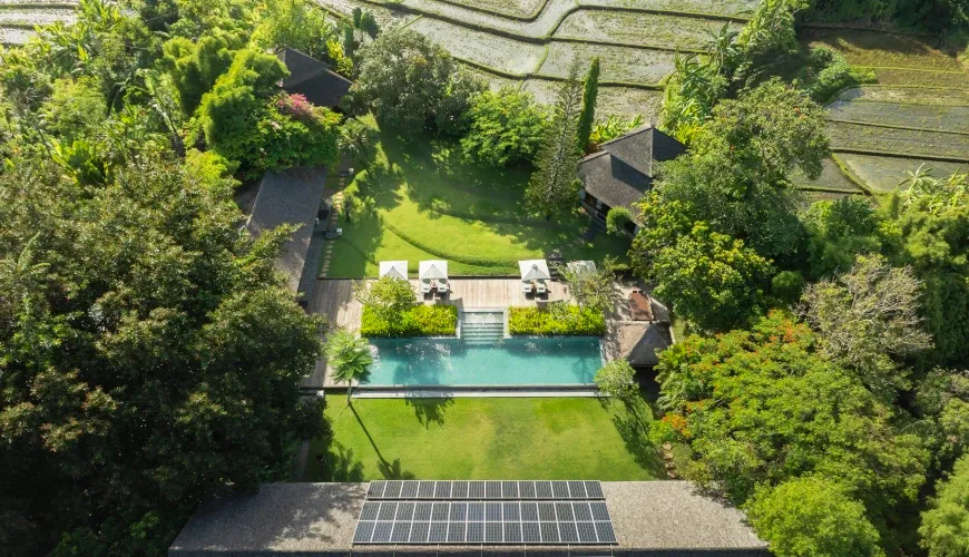Aerial view of a villa with a pool and lush greenery, bordering rice paddies at Villa Amita