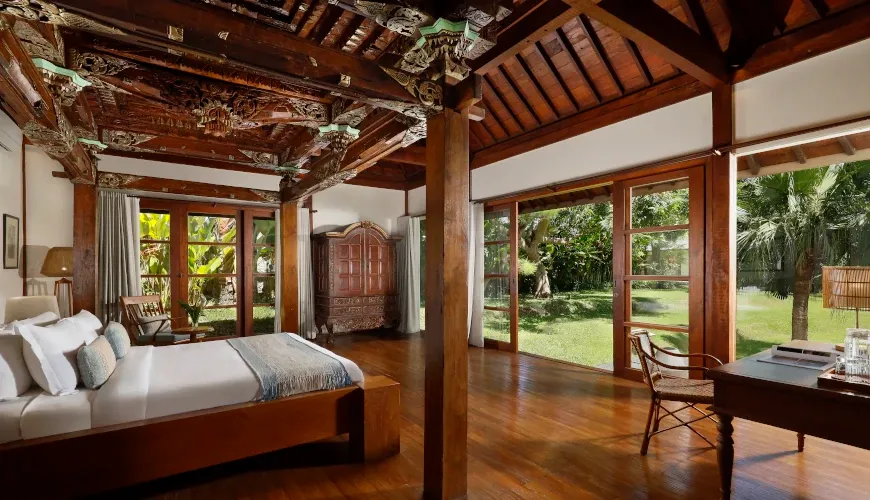 Ornate bedroom with carved wooden details and garden view at Villa Amita