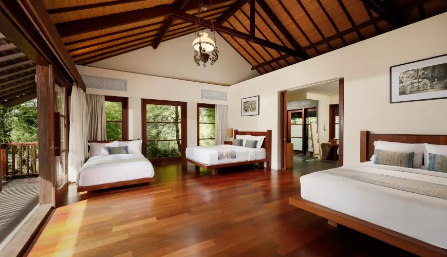 Spacious bedroom with three beds and wooden floors at Villa Amita