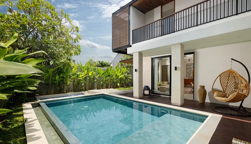 Private villa swimming pool with stylish hanging chair and lush greenery at Villa Ananya
