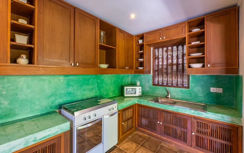 A kitchen with wooden cabinets, bright green countertops, and a stove at Villa Angsa