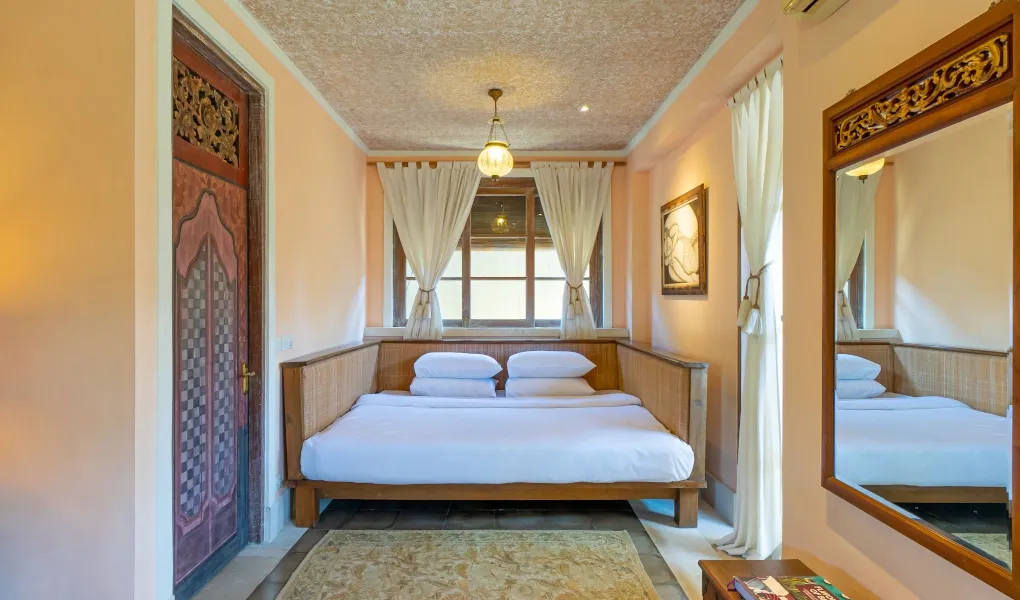 Bedroom with Balinese daybed and rustic patterned rug at Villa Angsa