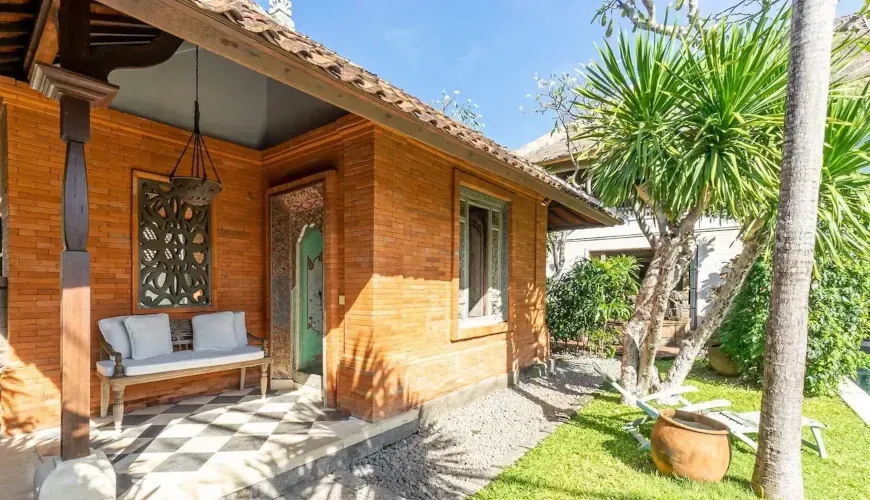 Charming brick villa exterior with a checkered patio, lush tropical garden, and blue sky at Villa Angsa