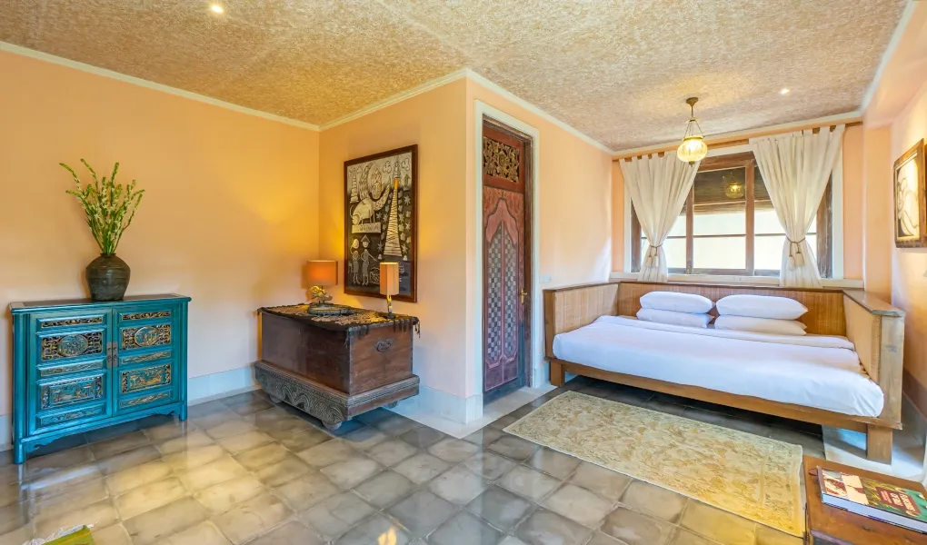 Cozy bedroom with traditional Balinese furniture and peach walls at Villa Angsa
